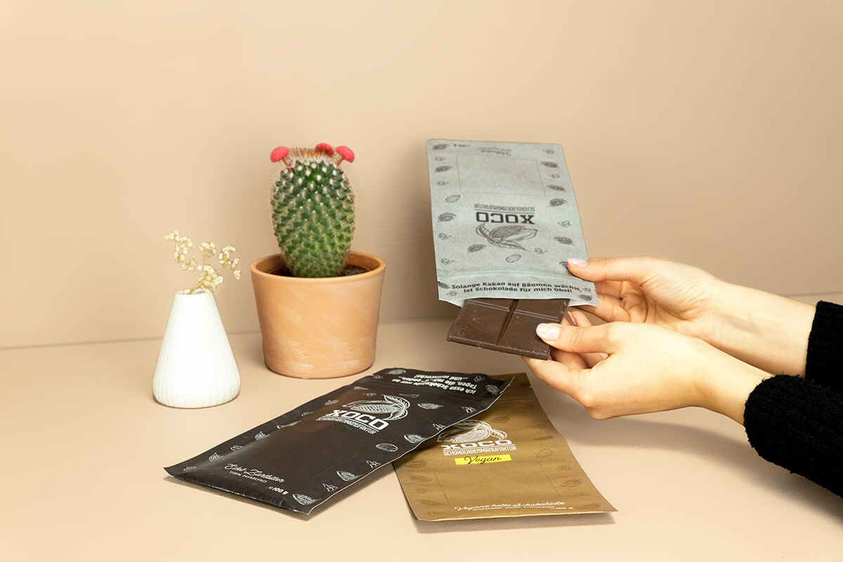 Hände greifen eine Tafel Schokolade aus einem Flachbeutel