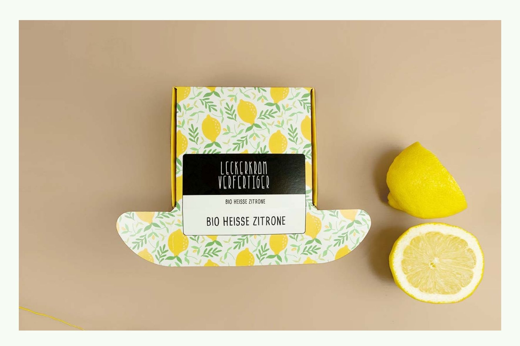 Scatola pieghevole stampata con motivo al limone accanto a limoni freschi Scatola pieghevole stampata con motivo al limone accanto a limoni freschi