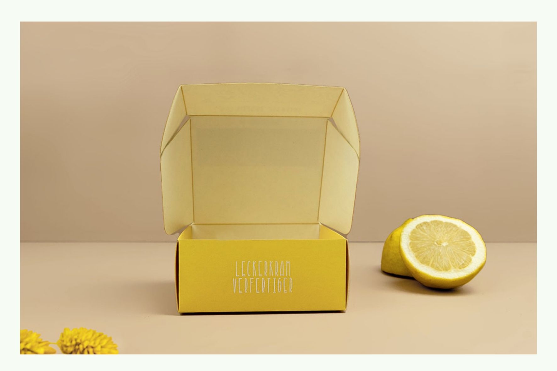 Scatola pieghevole gialla aperta accanto a mezzo limone Scatola pieghevole gialla aperta accanto a mezzo limone