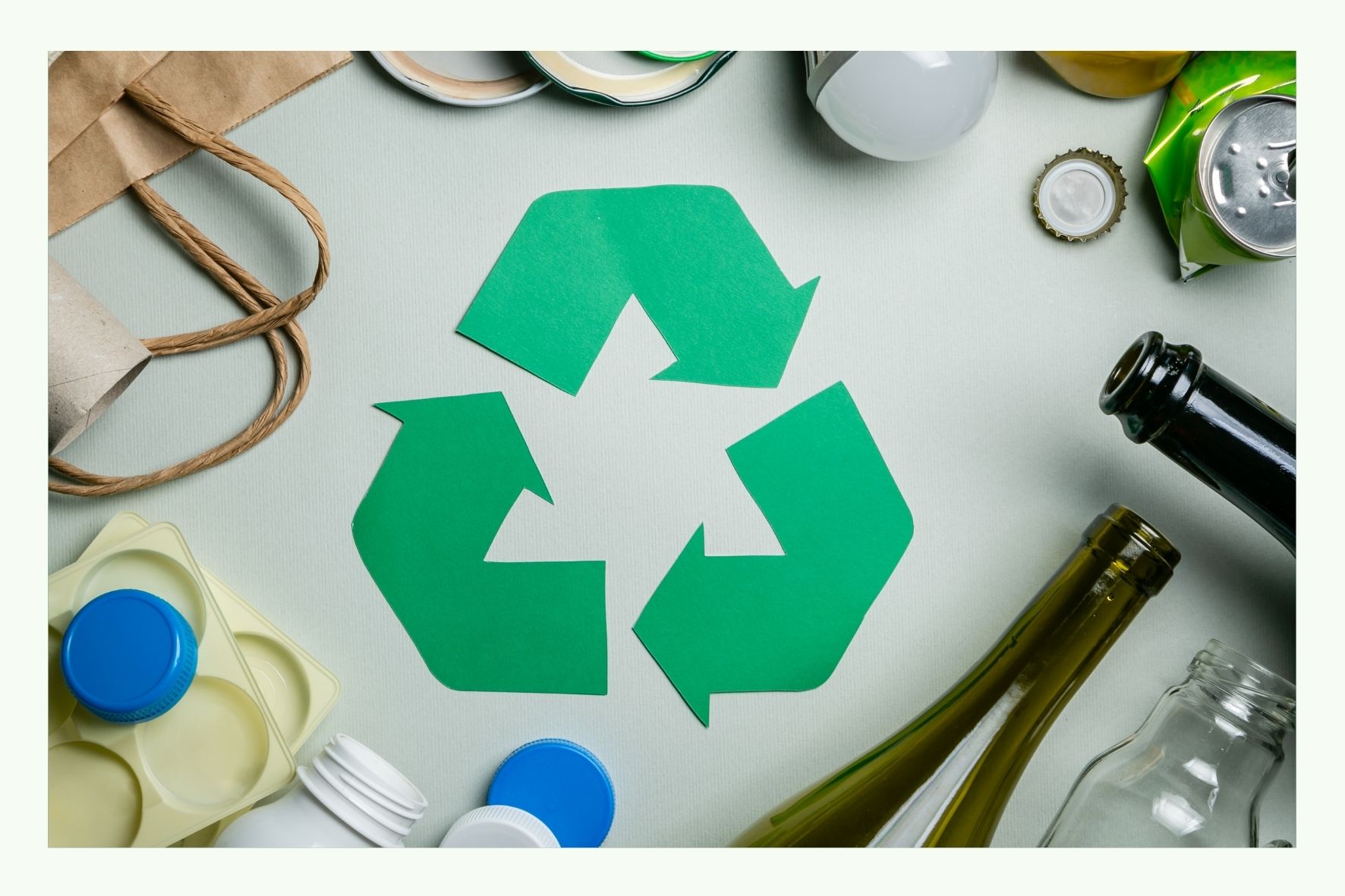 Green recycling symbol surrounded by various packaging materials Green recycling symbol surrounded by various packaging materials