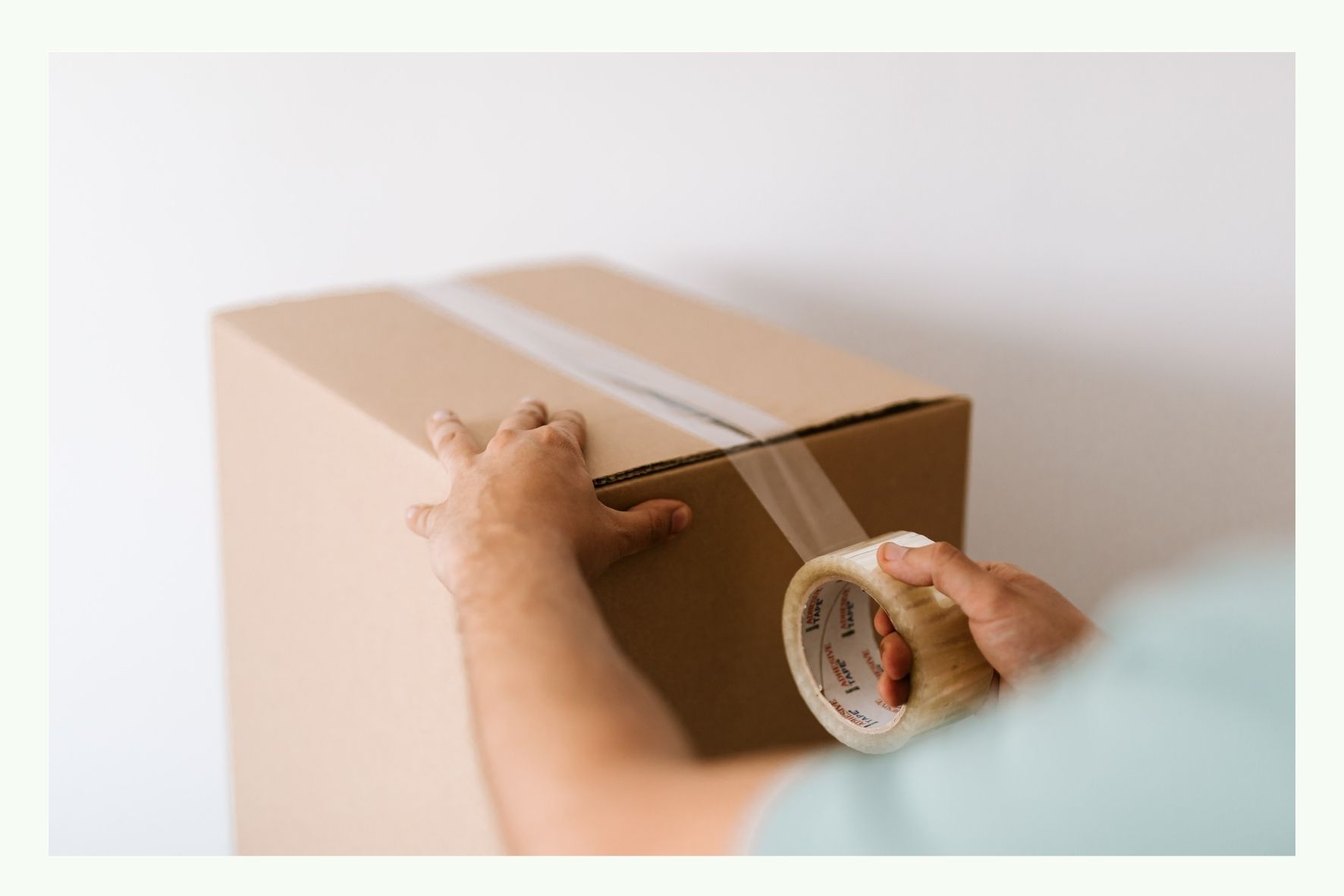 Persona che sigilla una scatola di cartone con nastro adesivo marrone Persona che sigilla una scatola di cartone con nastro adesivo marrone