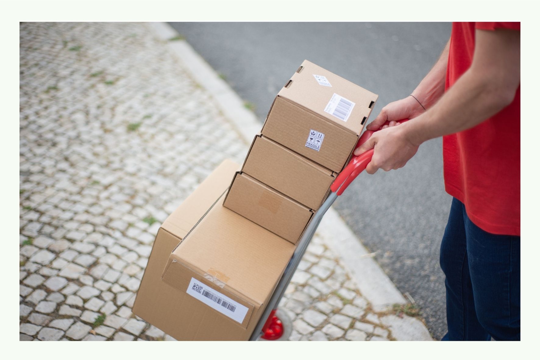 Persona che trasporta diversi cartoni da spedizione con un carrello a mano Persona che trasporta diversi cartoni da spedizione con un carrello a mano