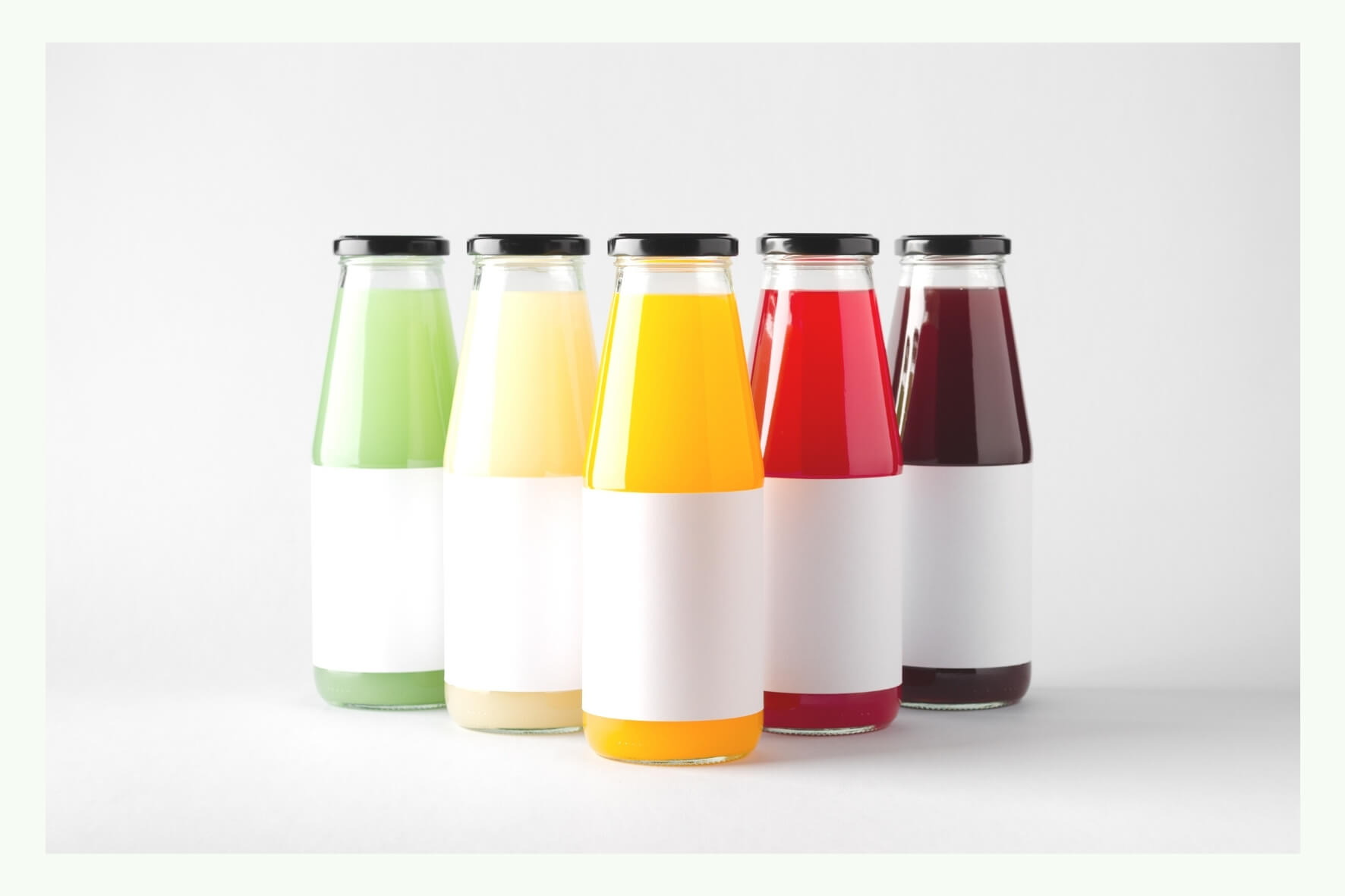 Diverse bottiglie di vetro con succhi colorati ed etichette bianche