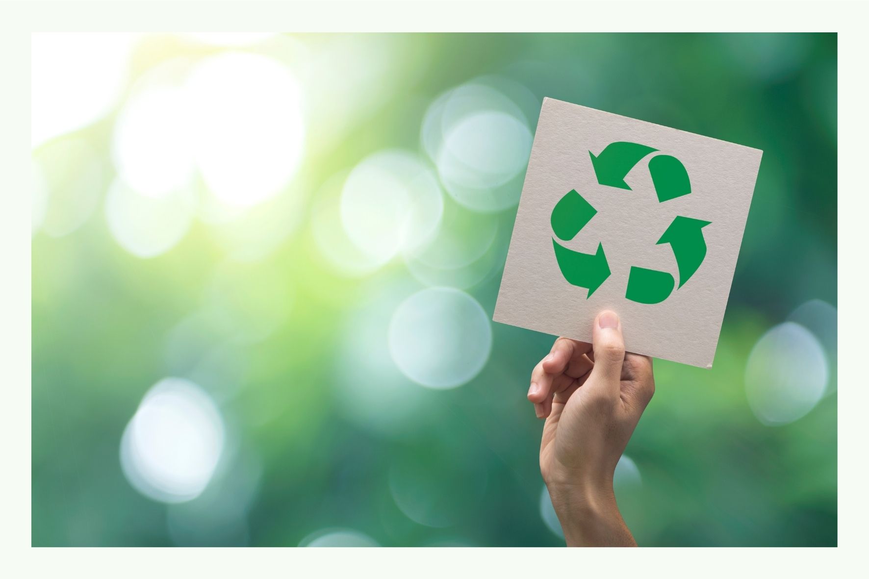 Hand hält Schild mit grünem Recycling-Symbol