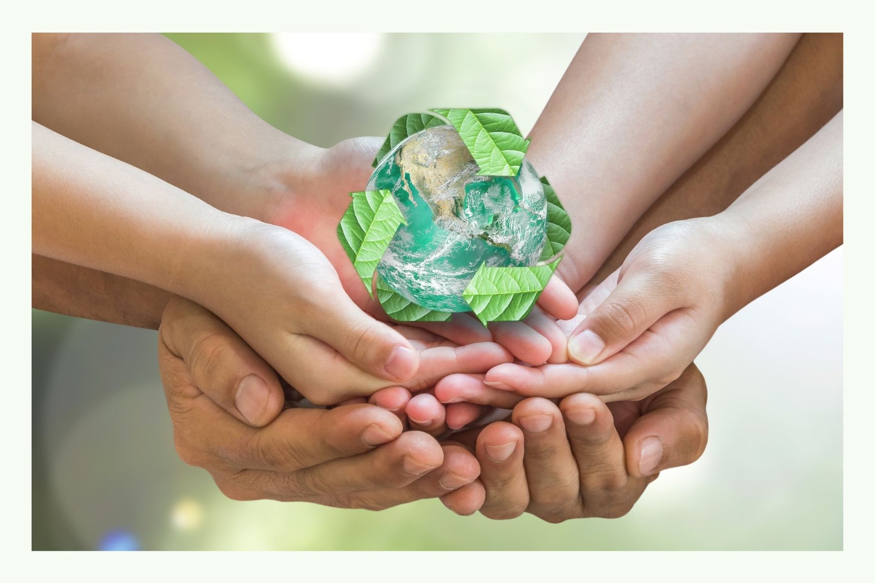 Mehrere Hände halten ein grünes Recycling-Symbol aus Glas