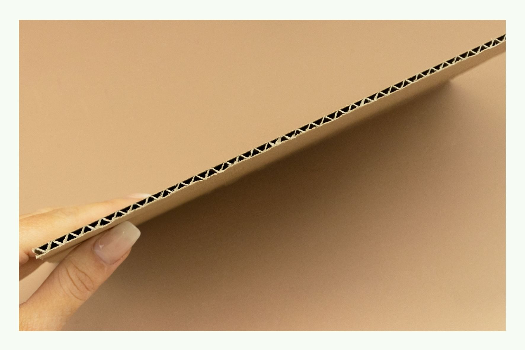 Hand hält eine Wellpappeplatte im Querschnitt