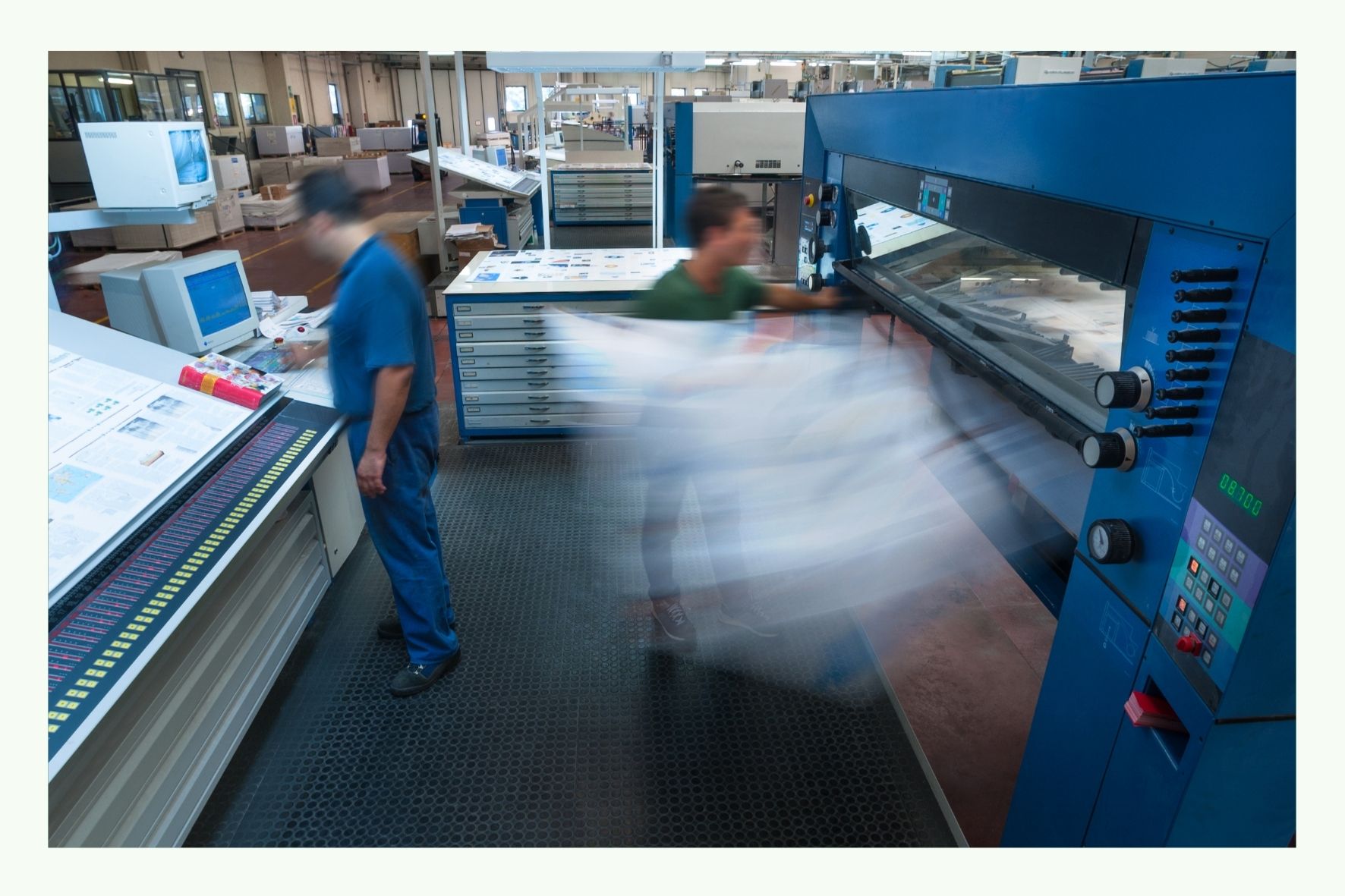 Operatori al lavoro su una grande macchina da stampa in un capannone di produzione Operatori al lavoro su una grande macchina da stampa in un capannone di produzione